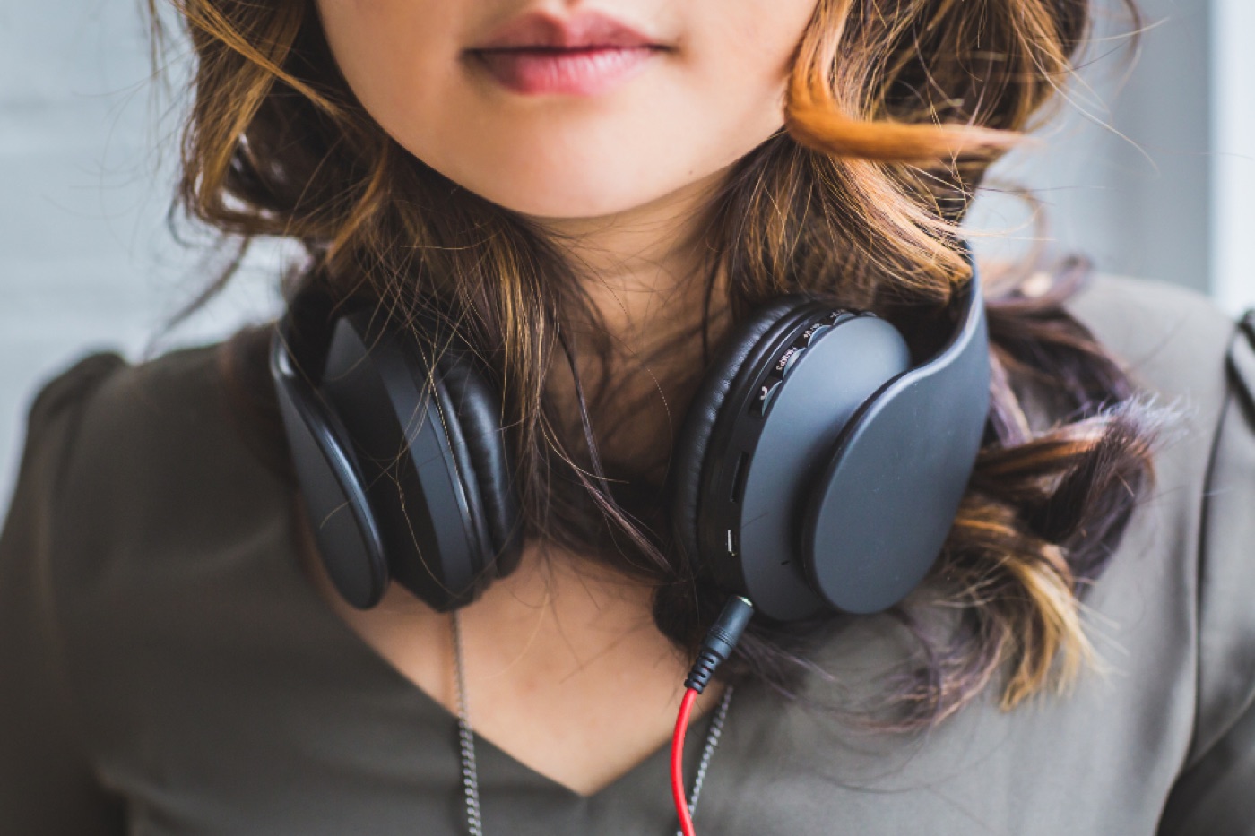 A woman in a sunlit room listening through headphones with a notebook in her lap.
