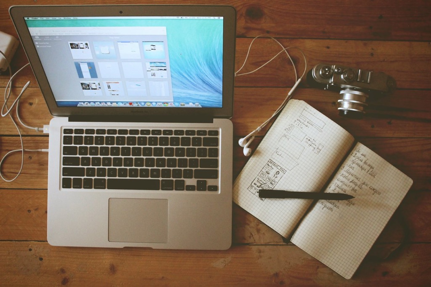 An open notebook with handwritten lines, a pen resting across the page, and a cup of tea nearby.