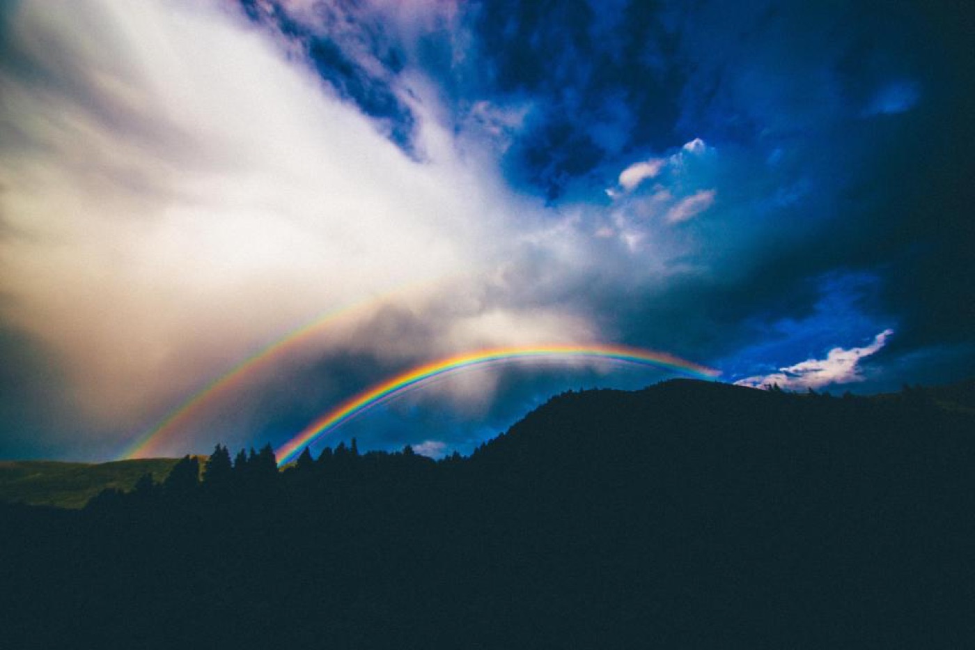 A soft rainbow arching over a dark violet sky after rain.